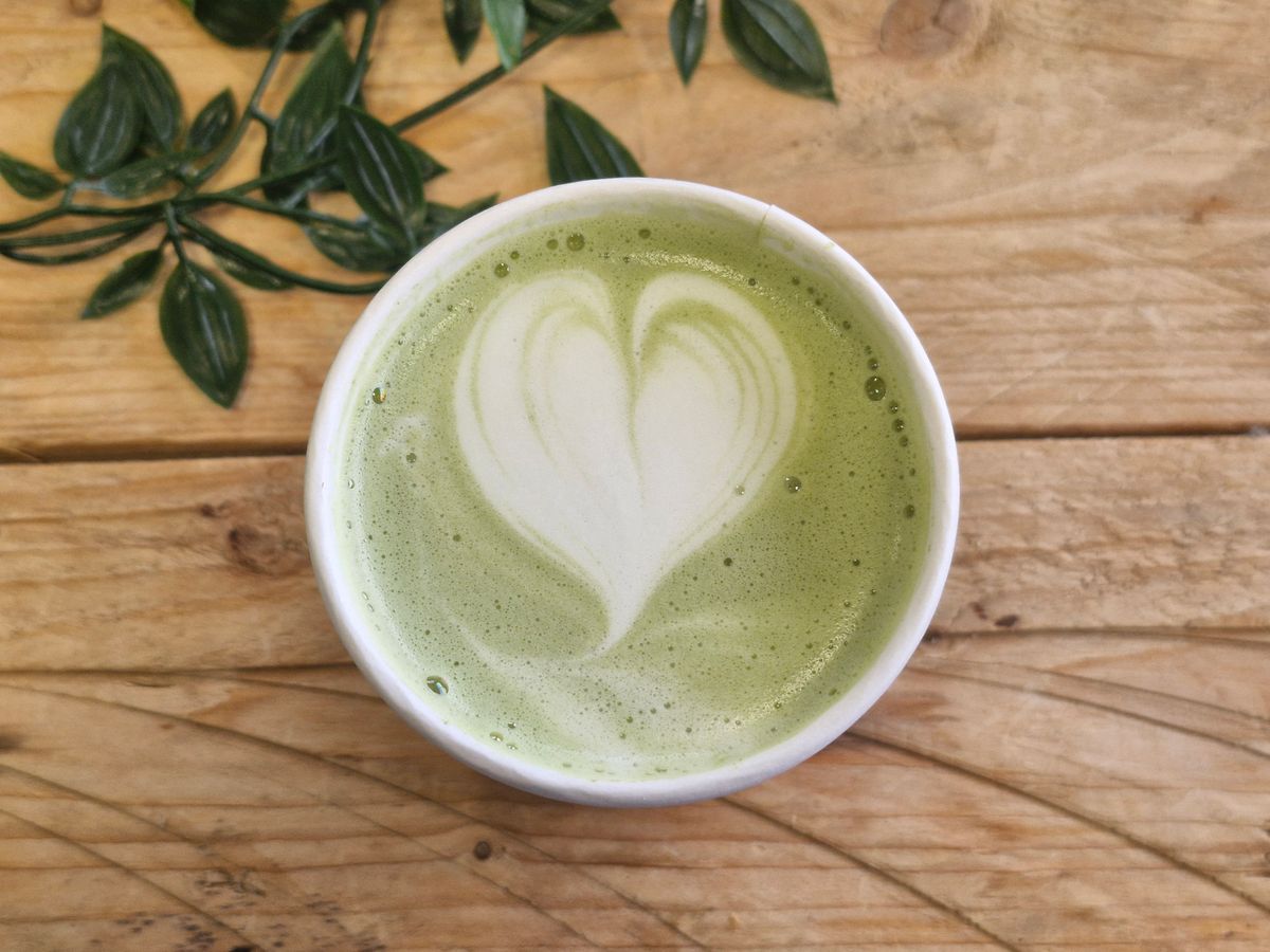 Matcha latte med hjärta i mjölkskummet på ett träbord