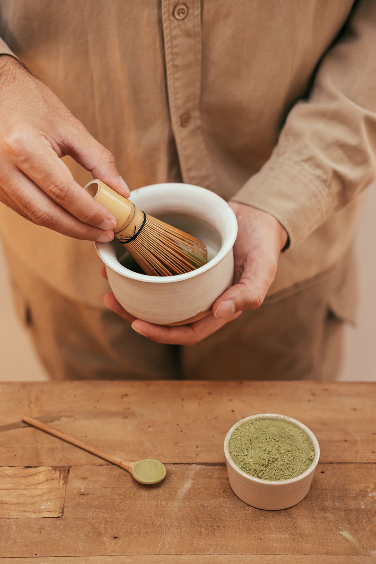 Matcha vispas för hand i en keramikskål vid ett träbord
