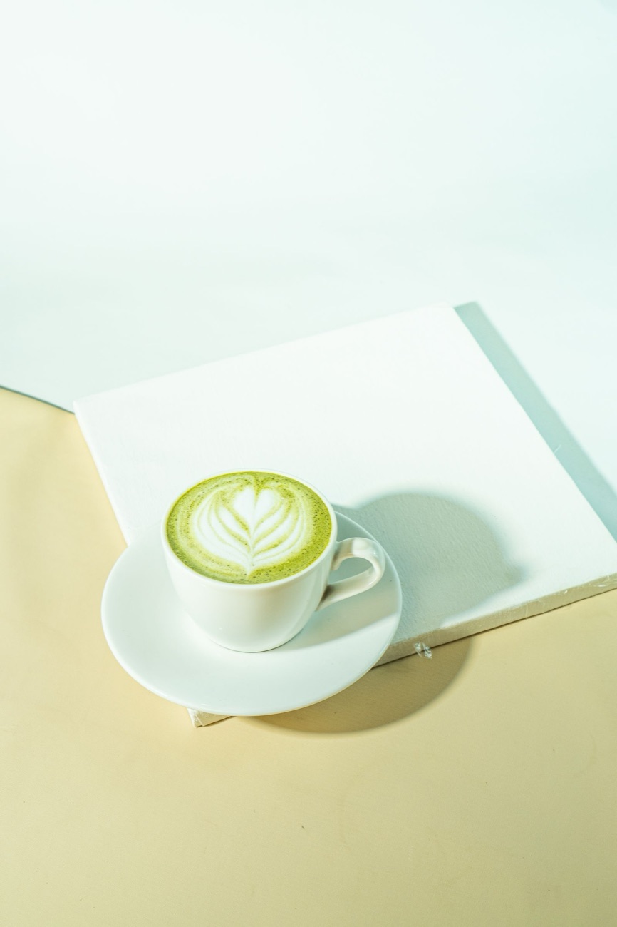 Varm matcha latte med vispad konst i en vit kopp